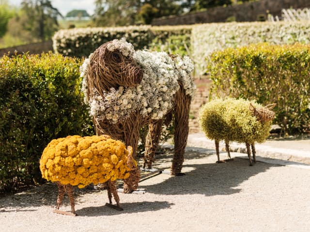 A set of three willow creatures decorated with foliage and flowers