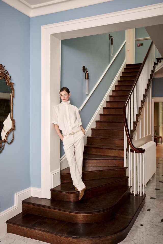 A woman leans on the staircase of Yarlington Lodge