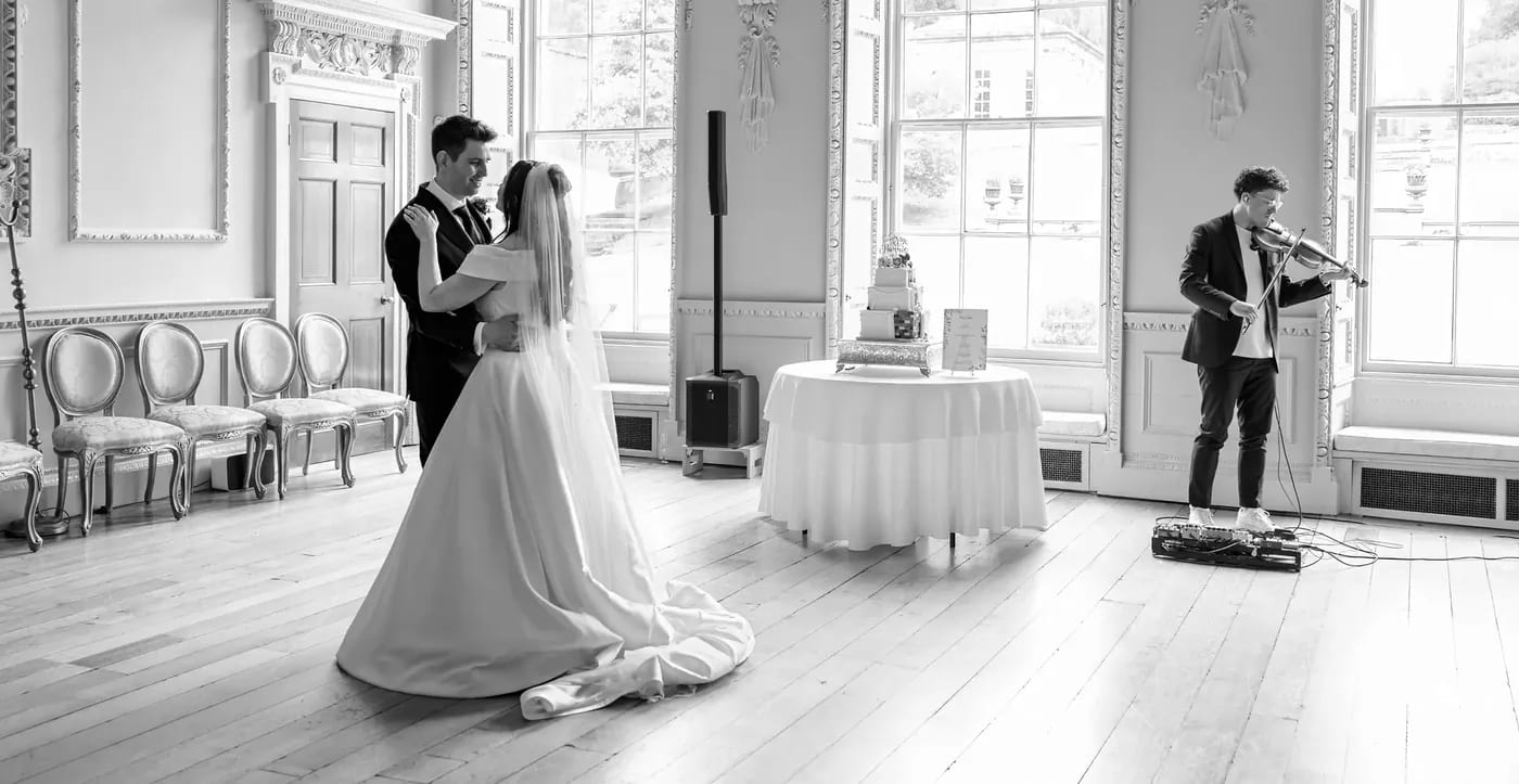 A couple sharing their first dance in a country house ballroom while Joel Grainger plays violin