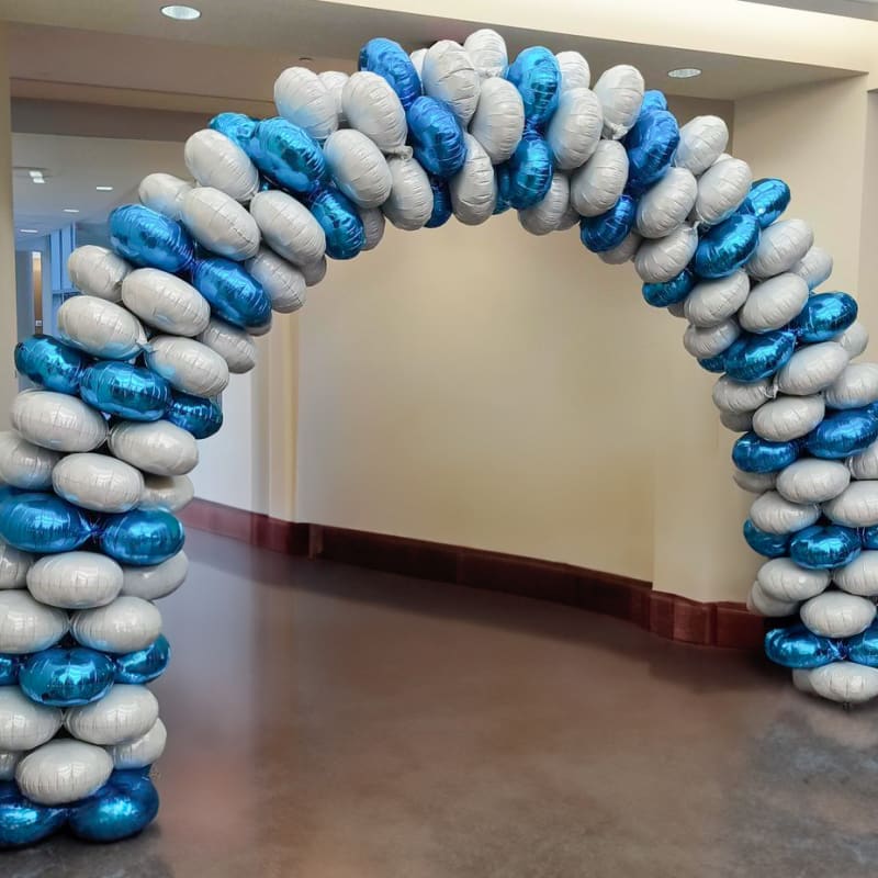 A decorative balloon arch in shades of blue and white stands in a hallway, creating an inviting and festive atmosphere.