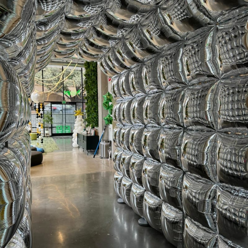 The image depicts a large indoor space filled with stacks of used tires, creating a visually striking and textured environment. In the background, a glimpse of a more open area can be seen, suggesting a larger facility or warehouse setting.