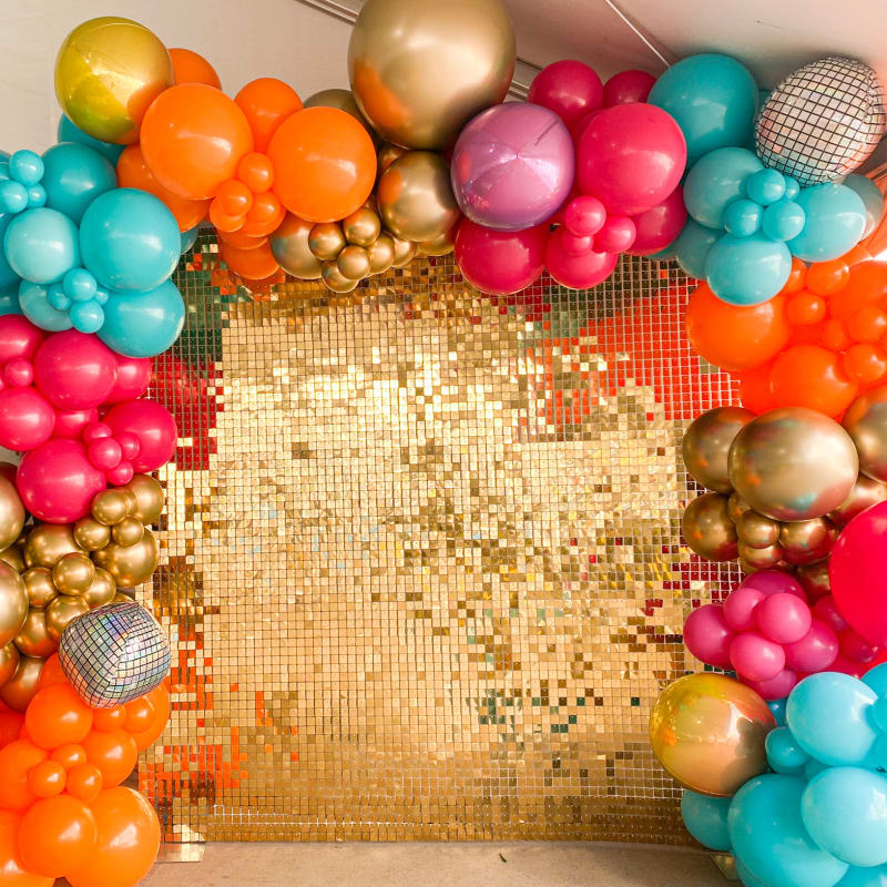 a bunch of balloons are arranged in the shape of a square with a gold sequin backdrop and a gold sequin backdrop