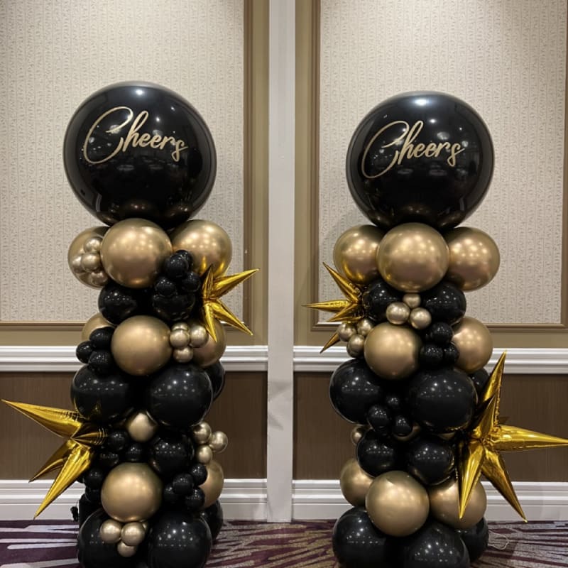 a couple of black and gold balloons sitting on top of each other in front of a wall with gold stars