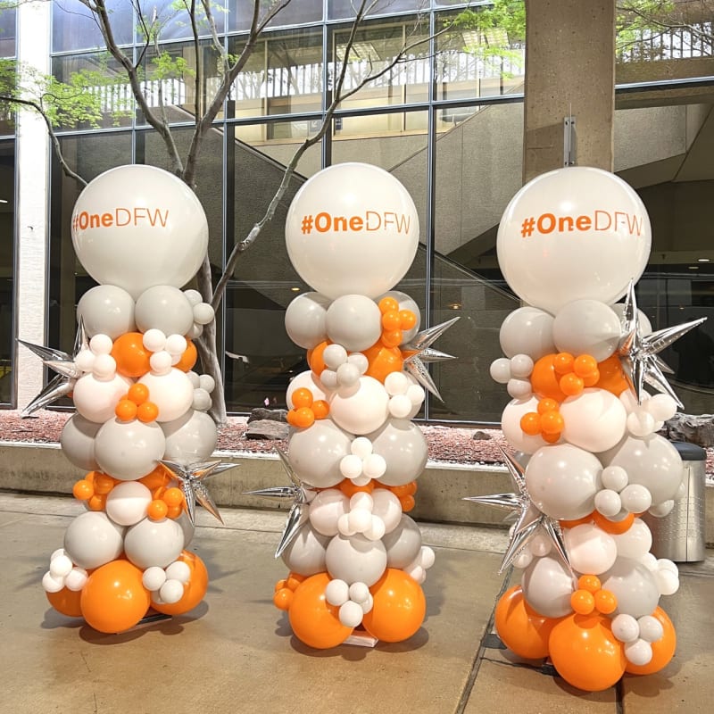 a bunch of balloons that are sitting on the ground in front of a building with a one df logo on it
