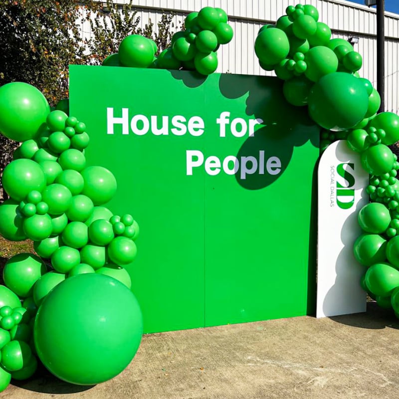 a green house for people sign with balloons in the shape of a tree and a bunch of green balls