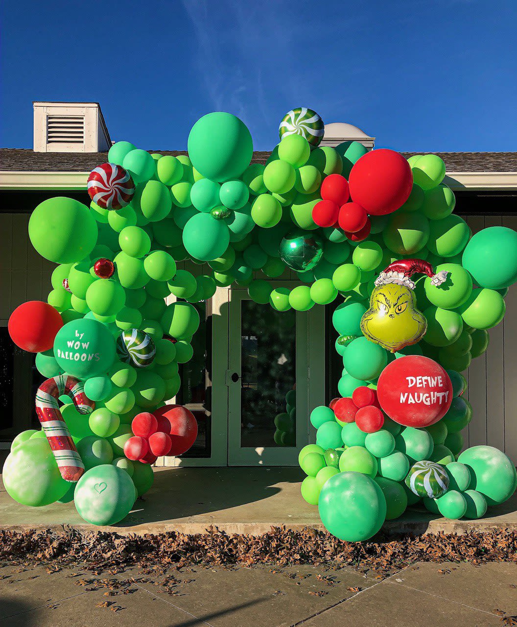 a large balloon arch in front of a house with a candy cane and candy canes on top of it