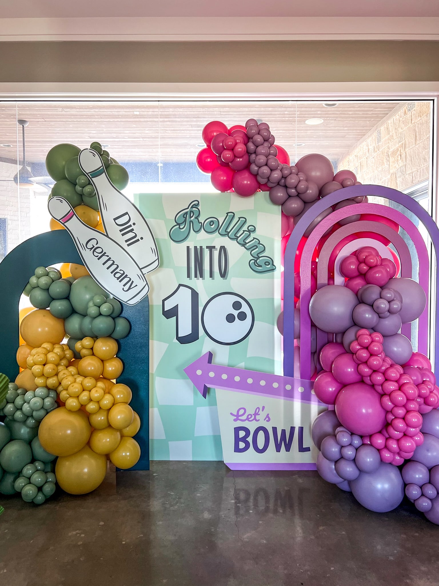 A vibrant and colorful display of various fruits, including grapes, olives, and other produce, arranged in an artistic and visually appealing manner, set against a backdrop of a playful and whimsical mural.