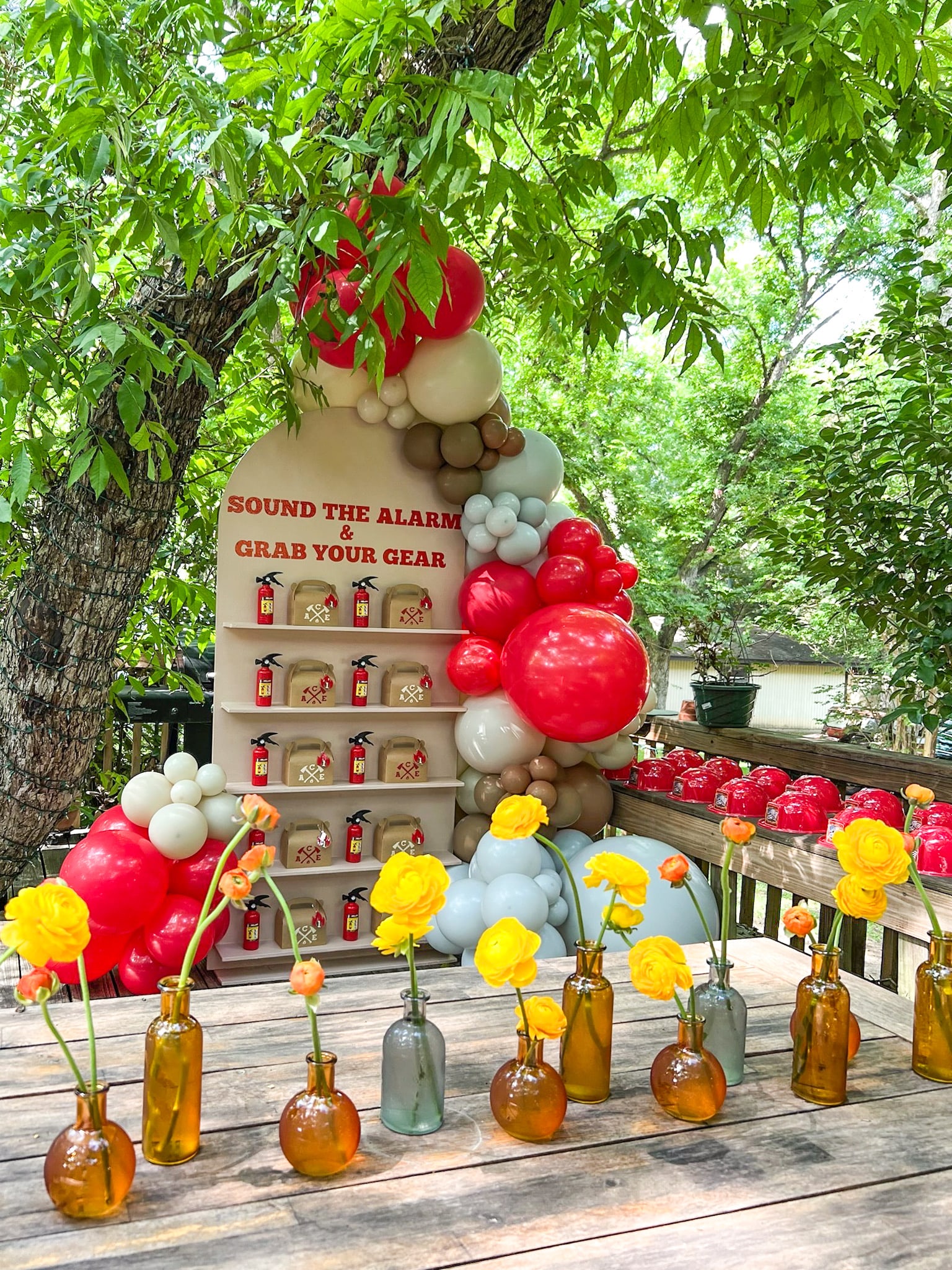 A vibrant outdoor display featuring an assortment of colorful vegetables, fruits, and decorative elements, set against a lush, green backdrop of foliage.