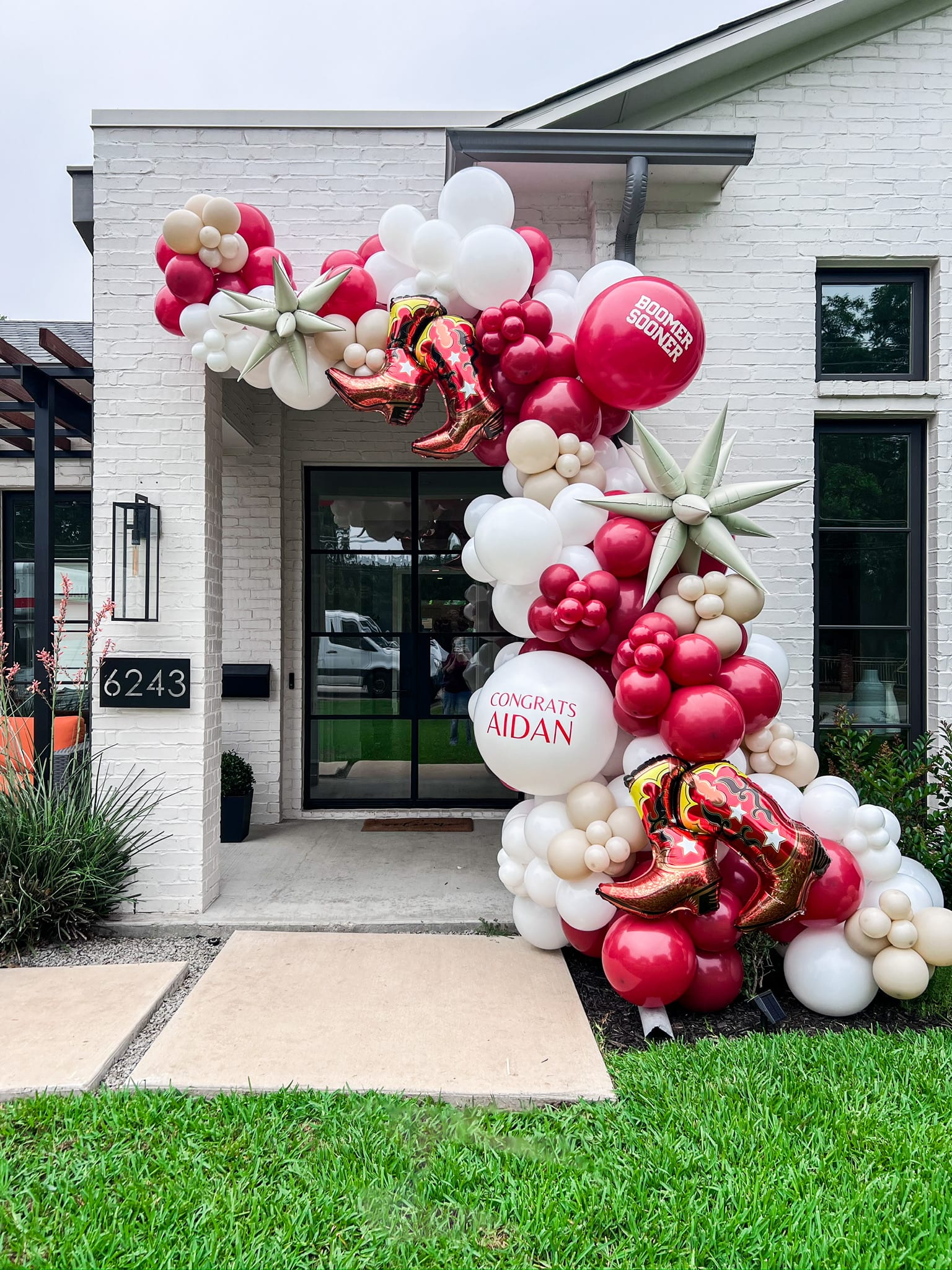 A vibrant display of red, white, and pink balloons adorns the entrance of a building, creating a festive and eye-catching scene against the backdrop of the structure's exterior.