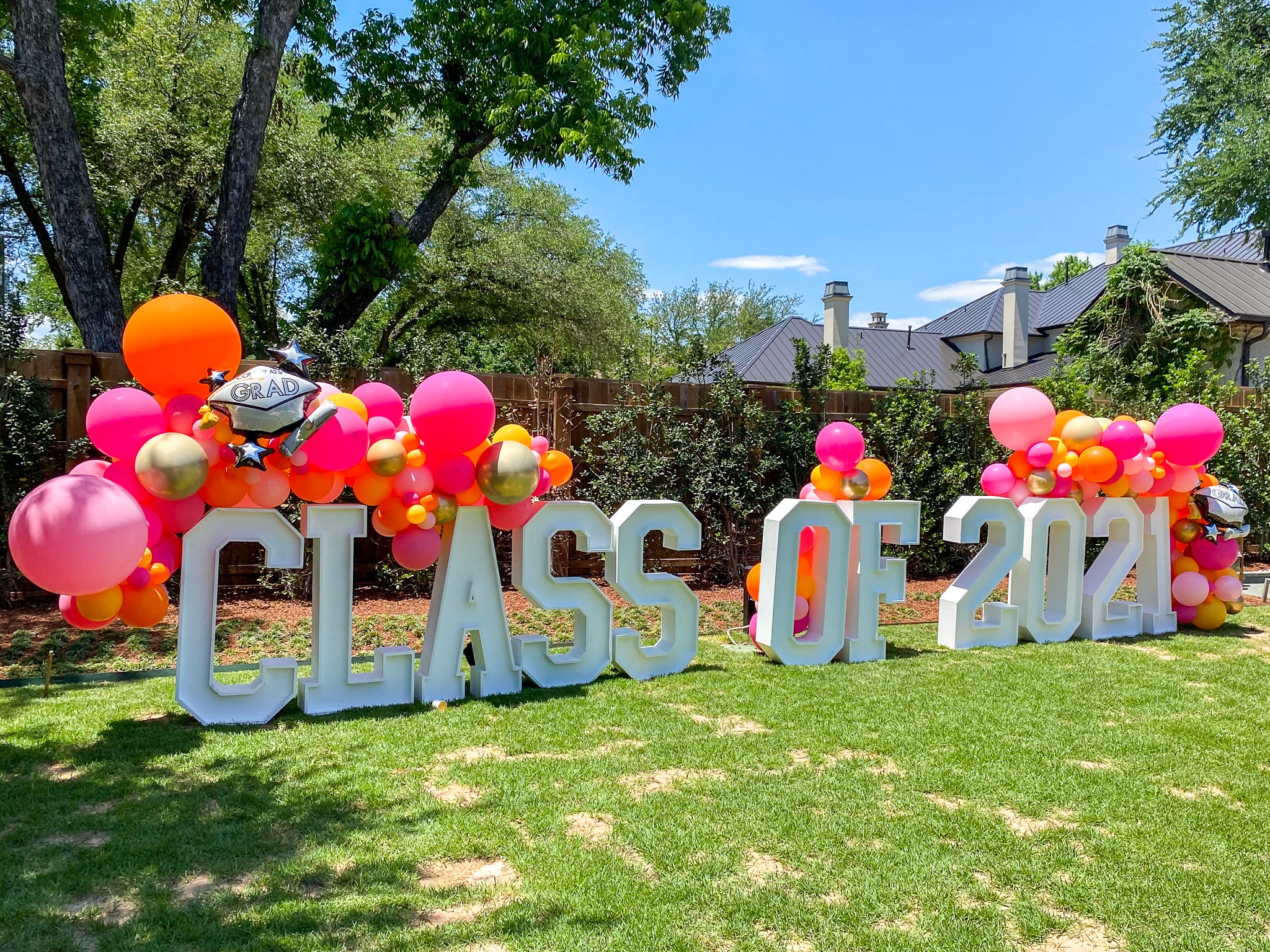 a lawn decorated with balloons and a large sign that says class of 2012 in the middle of the grass