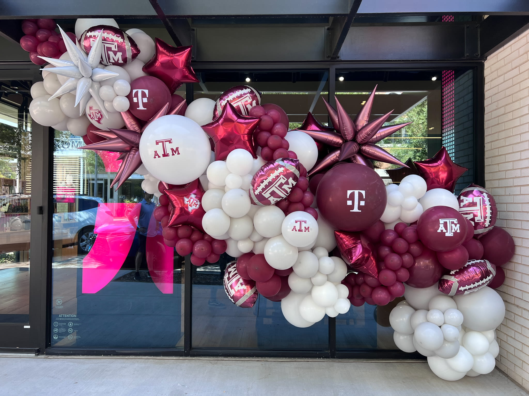 A vibrant and festive display of red and white balloons, stars, and other decorations adorns the storefront, creating an eye-catching and celebratory atmosphere.