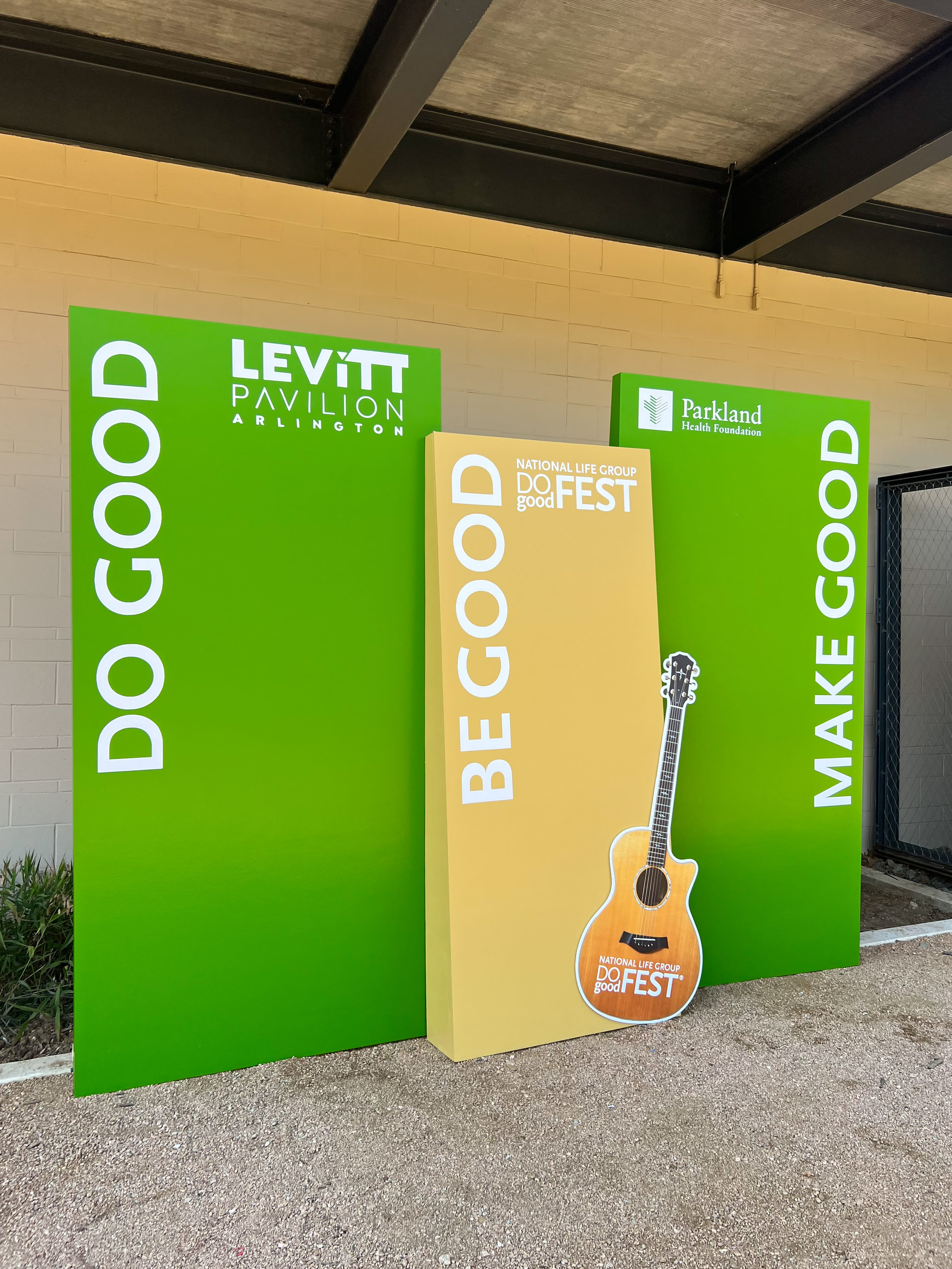 The image shows large green and yellow banners with the text "LEVITT PAVILION" and "PARKLAND FEST" prominently displayed, along with a graphic of an acoustic guitar, indicating an outdoor music festival or event.