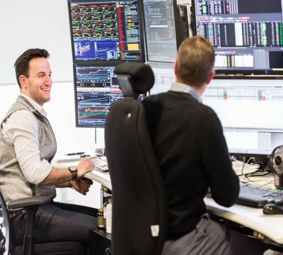 Photo of man working in front of monitor with stock market data