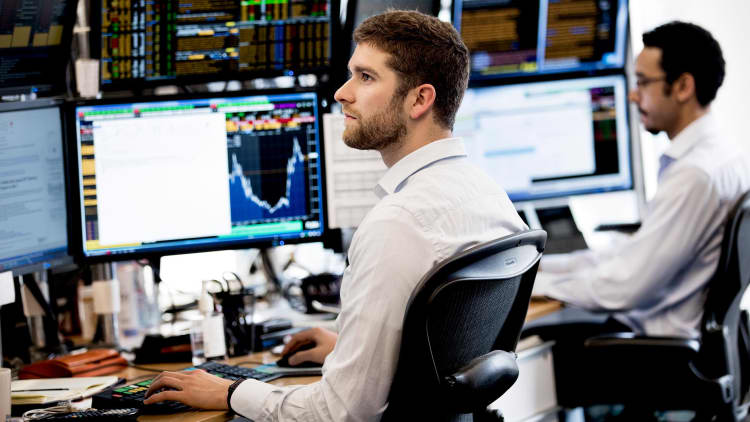 Two men reviewing financial data on computer monitors