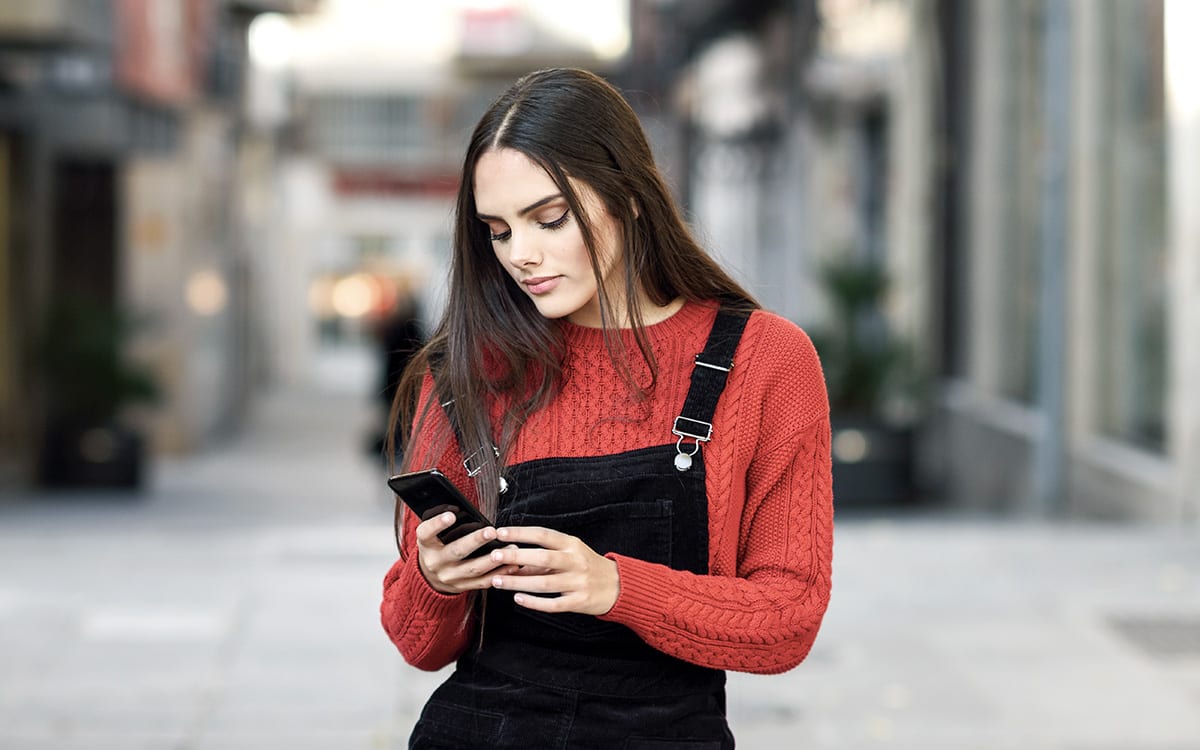 En ung kvinne ser ned på smarttelefonen sin