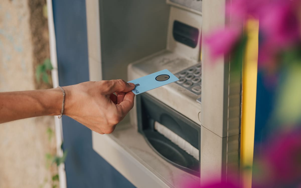 Hand som sätter in ett Bank Norwegian-kort i en bankomat för att ta ut kontanter