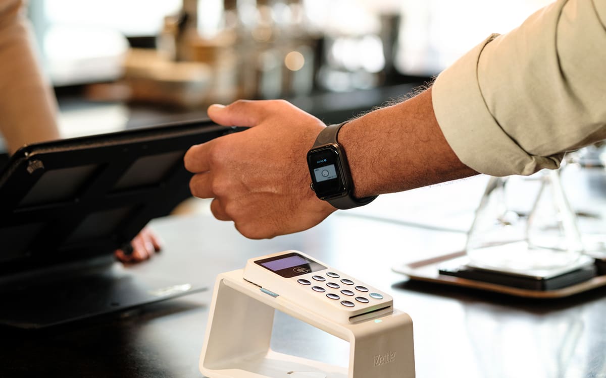 En person betaler kontaktløst med et smartwatch på en betalingsterminal.