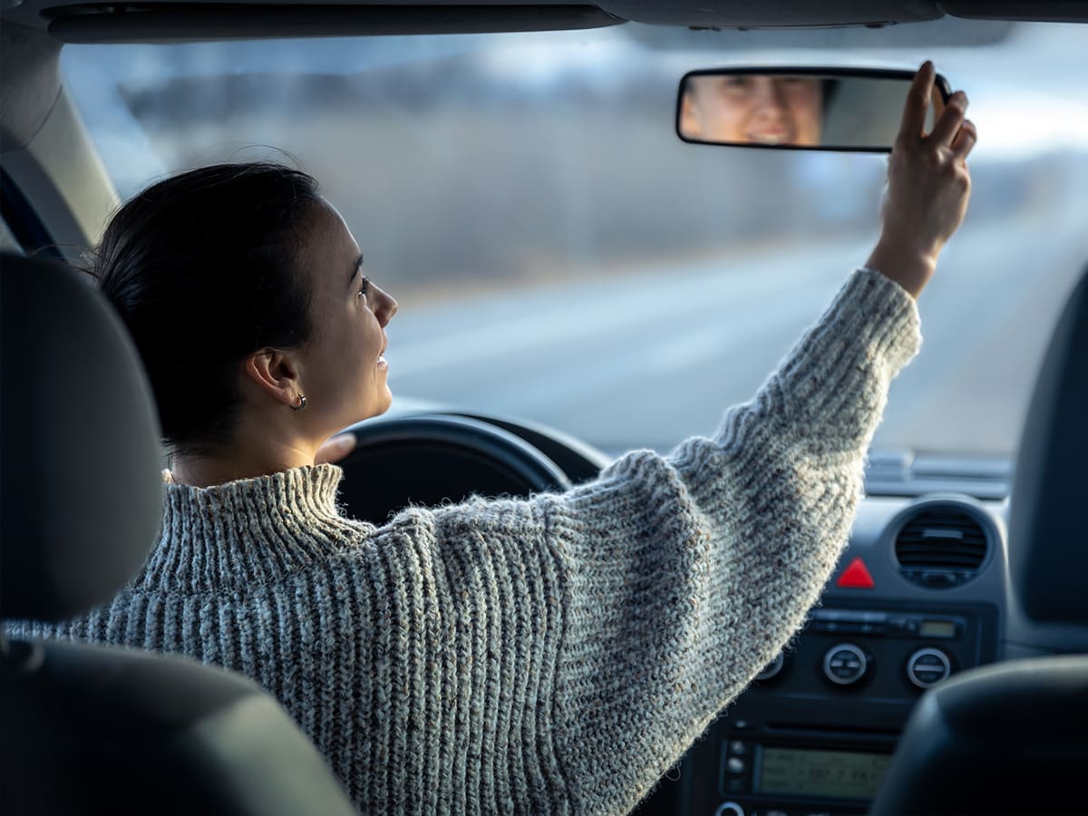 Nuori nainen säätää peiliä autossa