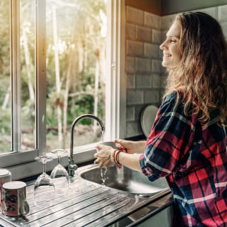 Kvinne vasker en kopp på sitt kjøkken