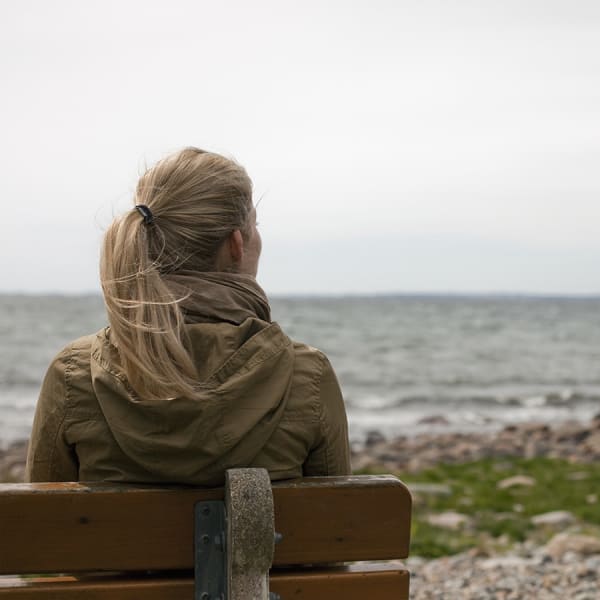 En ung kvinde sidder og kigger ud over havet