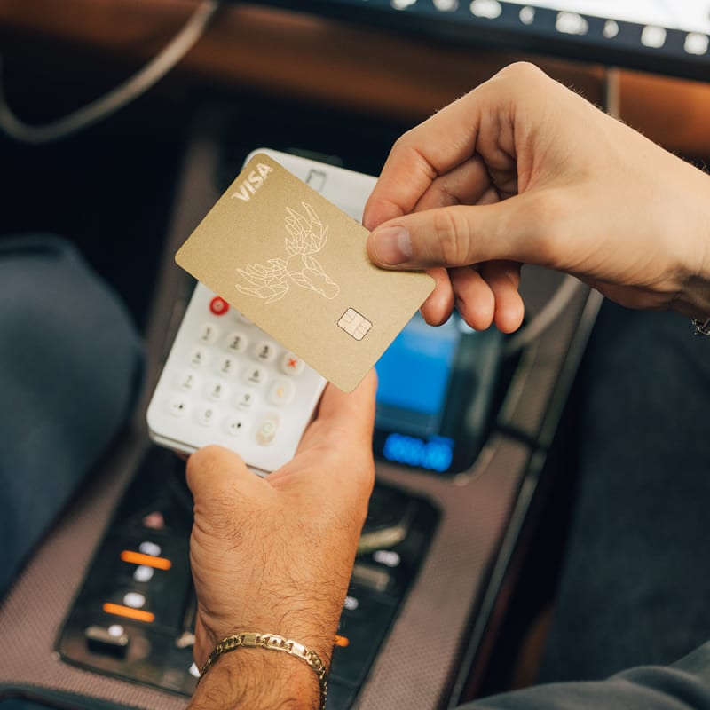 Taxifahrt bezahlen mit der Bank Norwegian Kreditkarte: goldene Visa-Karte am Kartenlesegerät