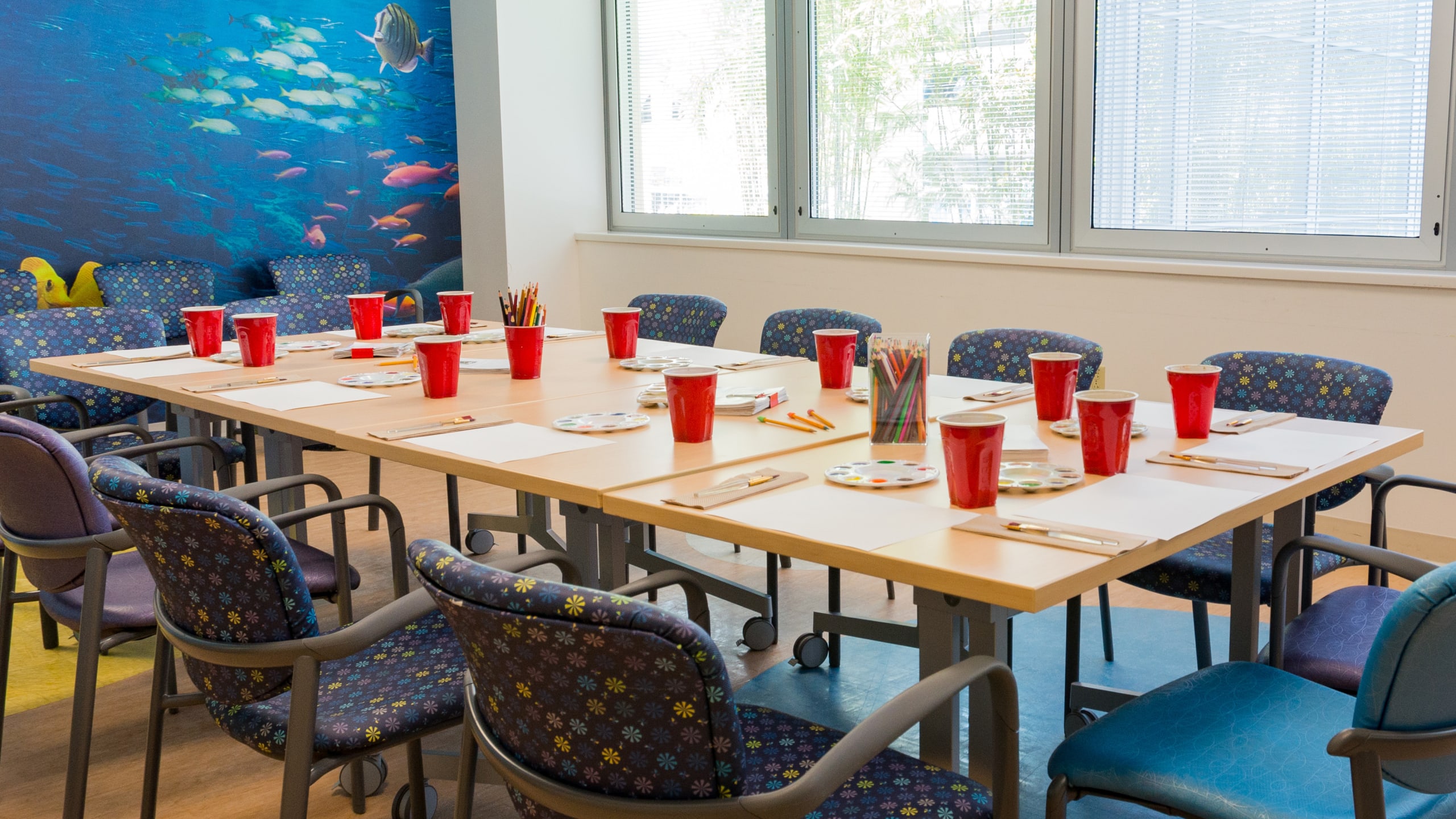 table set with individualized watercolor paint stations near the window of a brightly lit room
