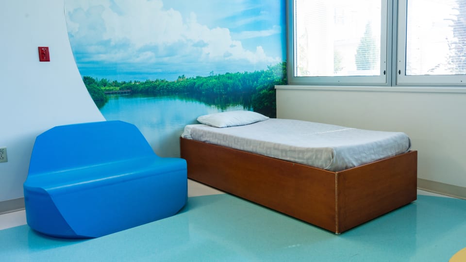 brightly lit inpatient room at Wolfson with a single bed and blue plastic couch