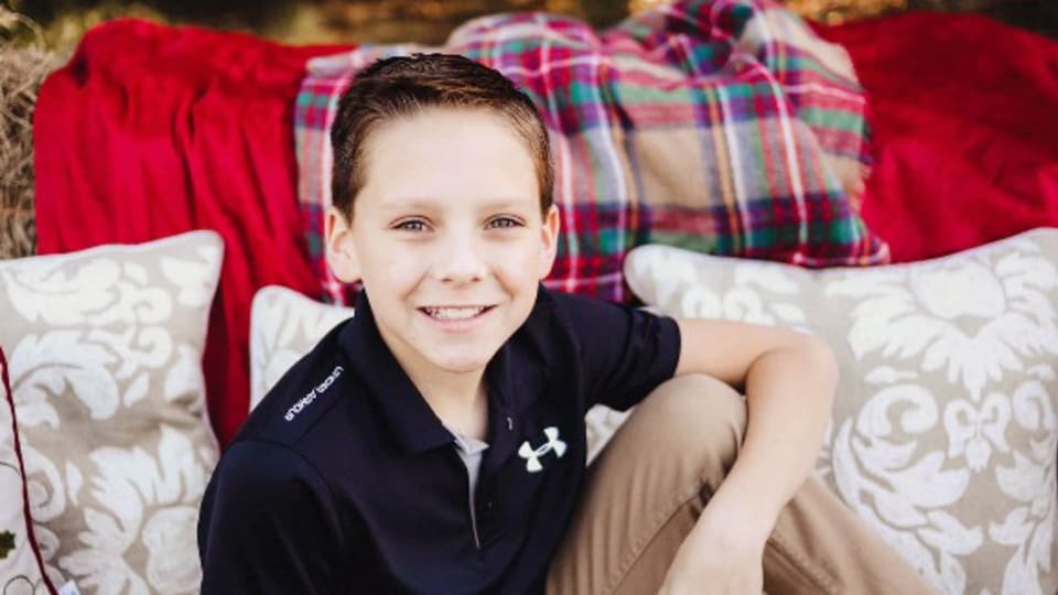 young patient smiles while he sits in front of pillows and hay bales