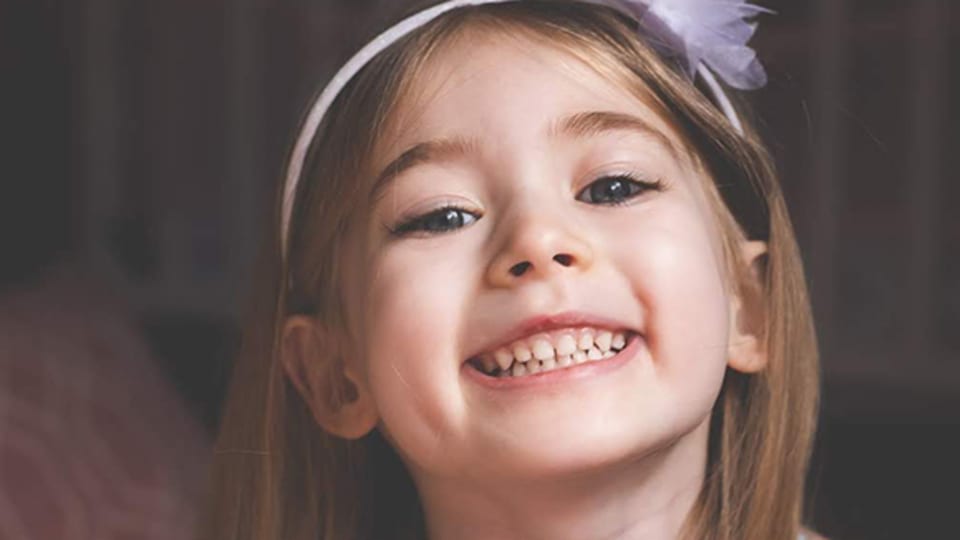smiling young girl wearing a pink headband