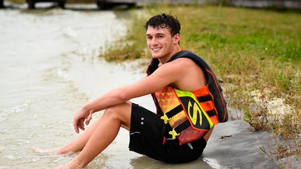 Johnnie 'Ryne' Jacobs sitting on the edge of the water with a life vest on