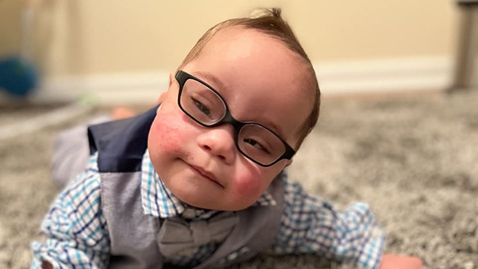 Neonatal surgery patient Malachi laying on the carpet