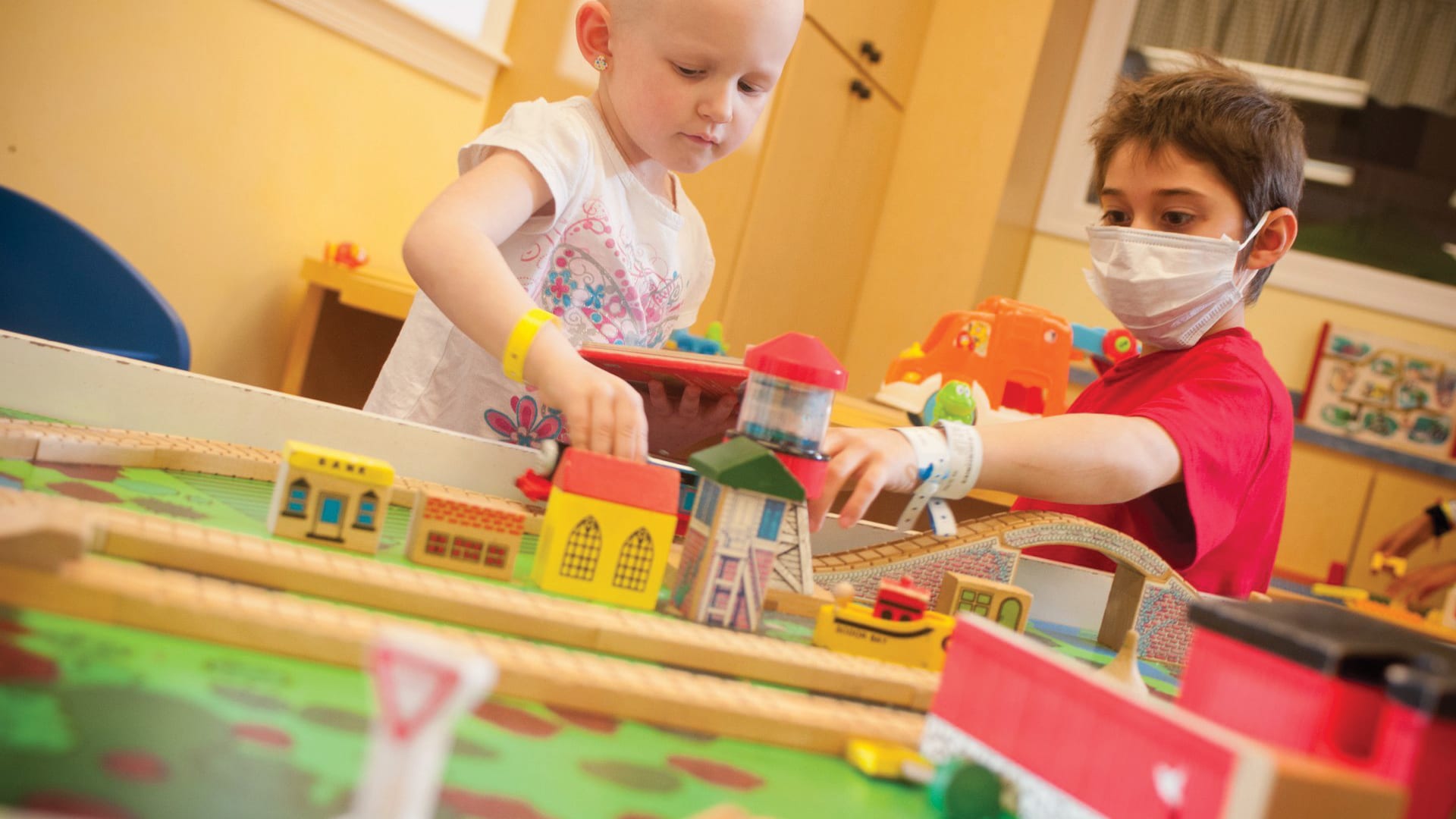 two young hospital patients playing with a wooden train set