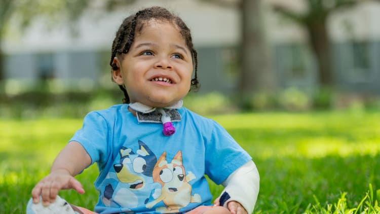 young child in an arm cast sitting outside in the grass
