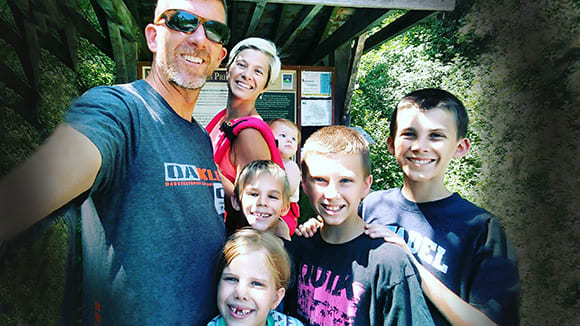 smiling family stands together outside at a park