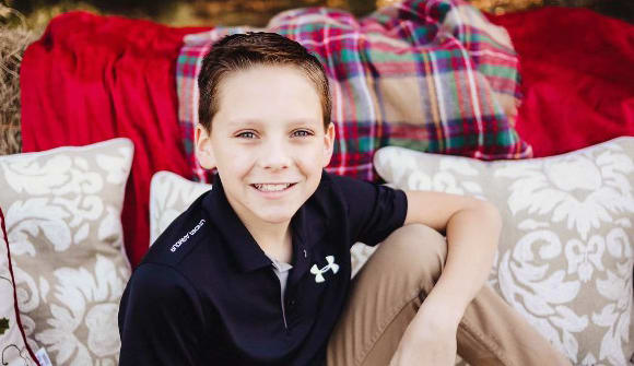 young patient smiles while he sits in front of pillows and hay bales
