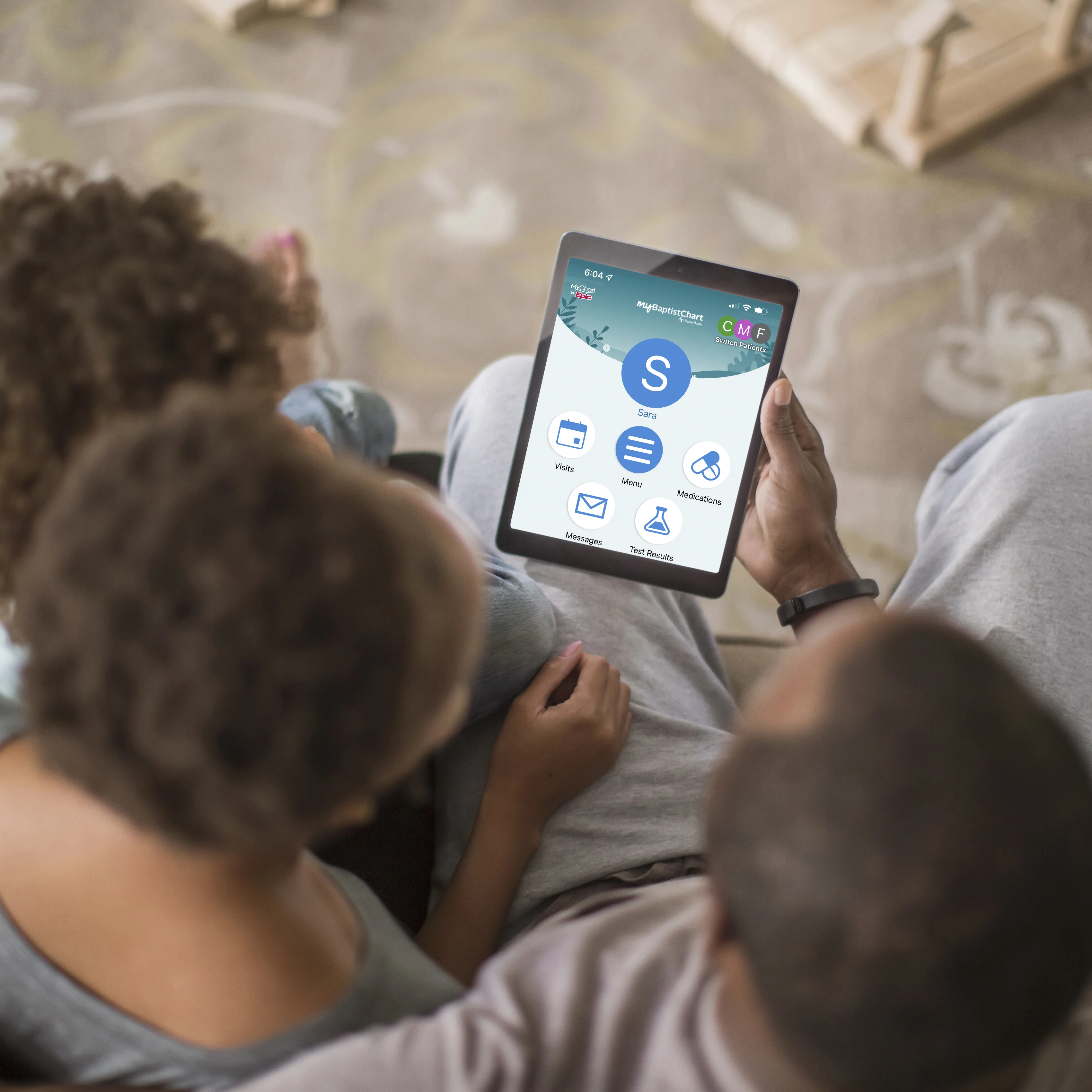 a family looks at their tablet that shows the home screen of the My Baptist Chart website.