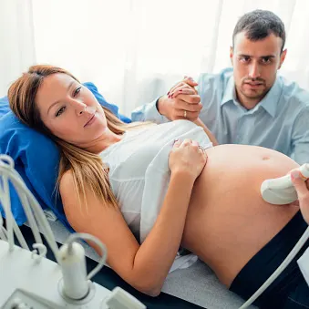 pregnant woman getting a sonogram while holding husband's hand