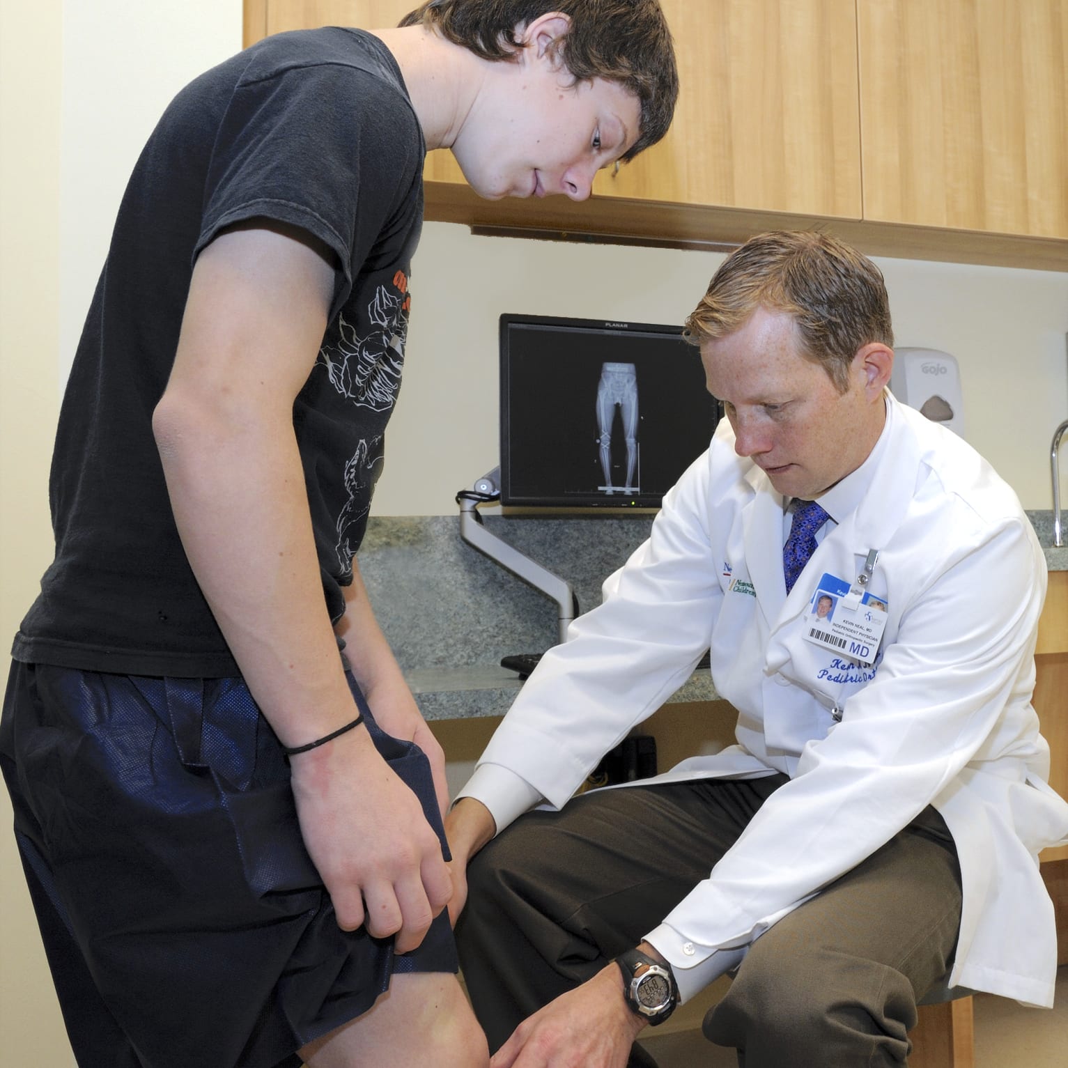 male doctor examining the knee of a teenage boy in a medical office