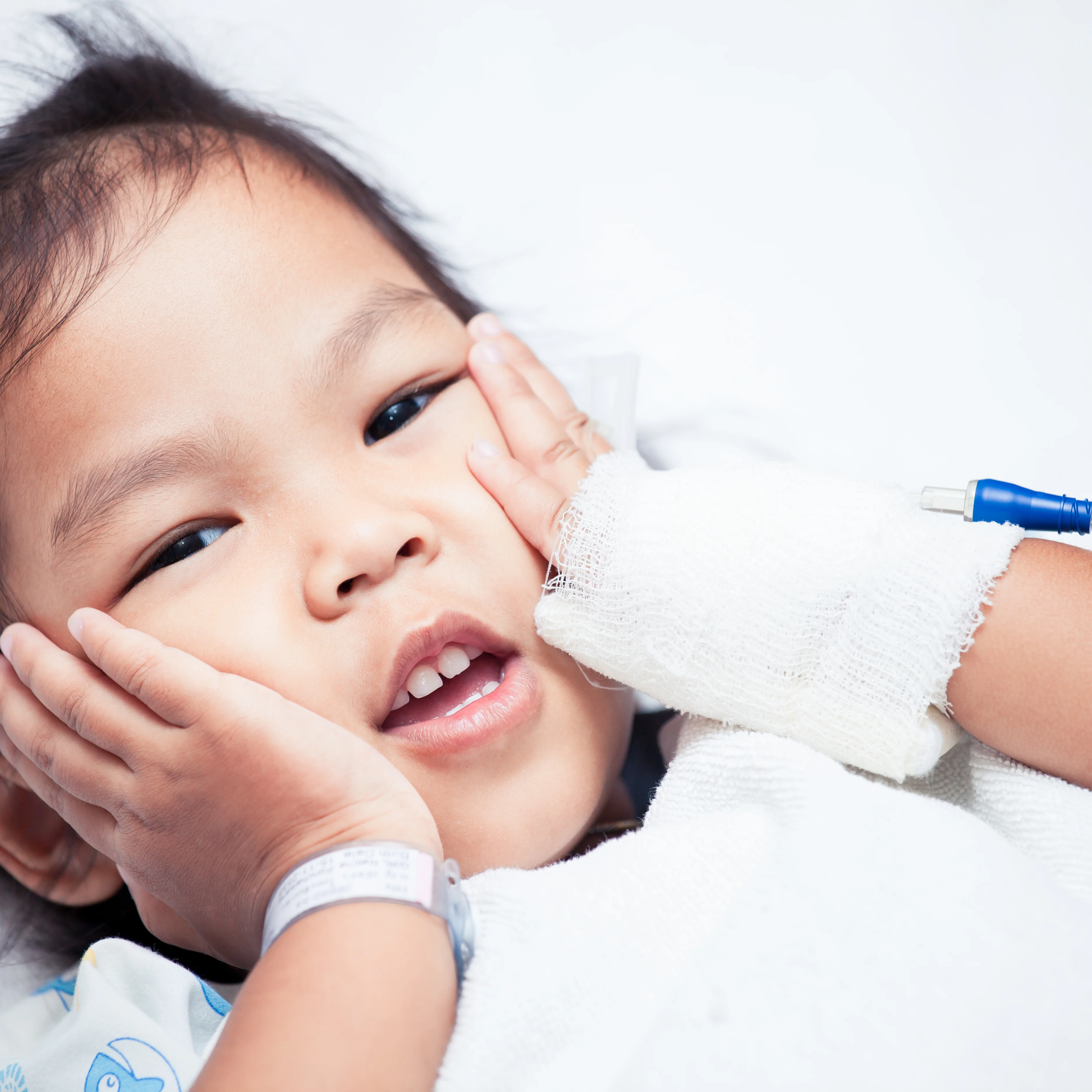 A sick asian child girl is lying on the bed and touching her face in the hospital