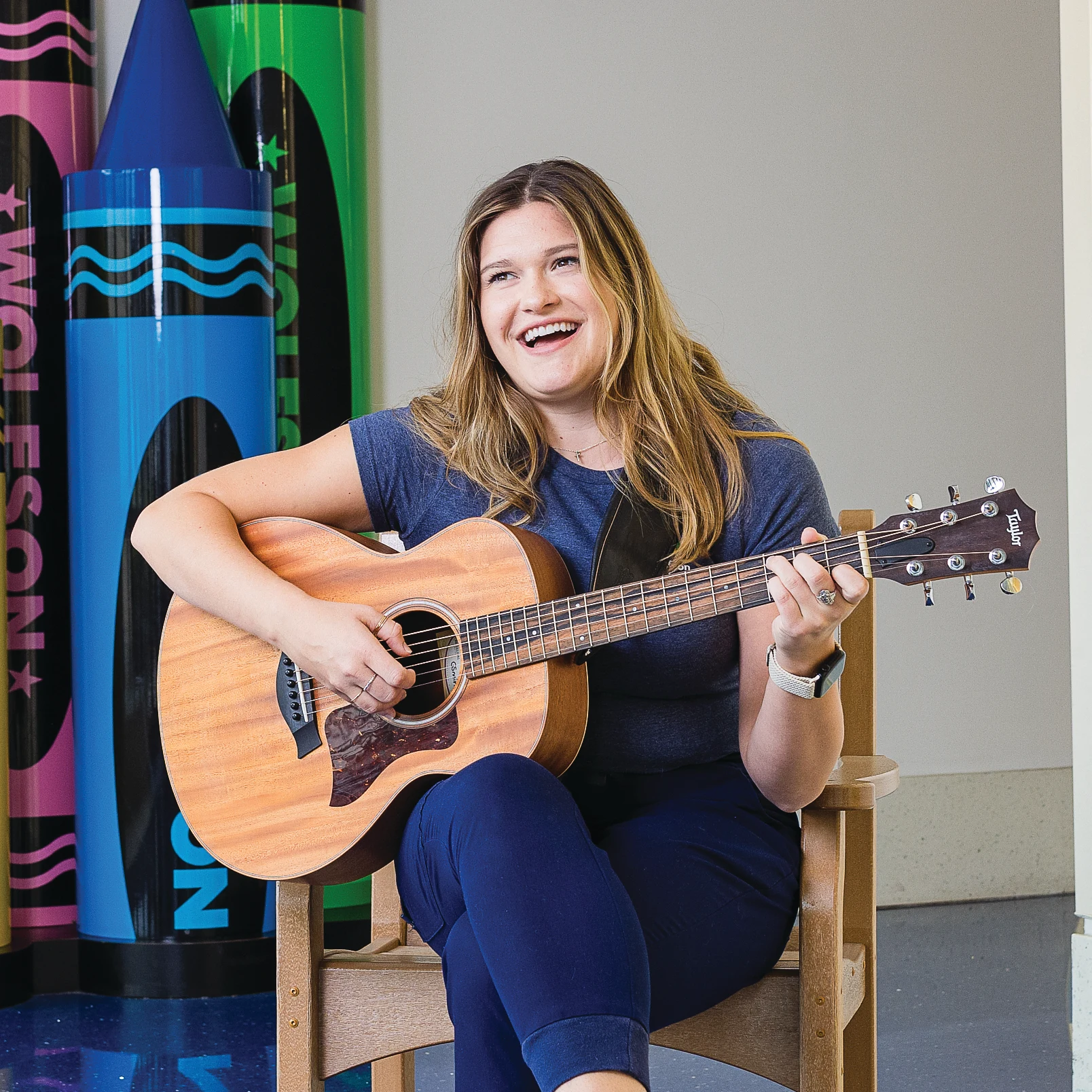 woman smiling and playing guitar in front of crayon sculpture at WCH