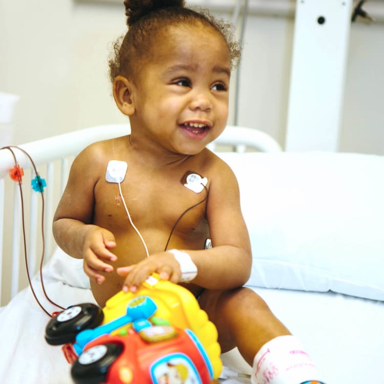 Child in hospital bed holding toy