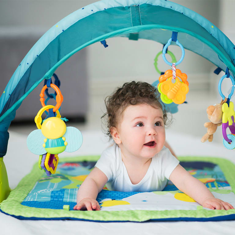 A baby plays on her tummy and looks at toys