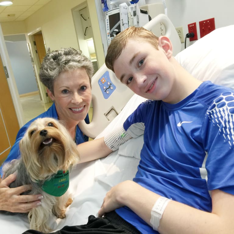 Pet therapy dog and trainer visit male pediatric patient at Wolfson Children's Hospital