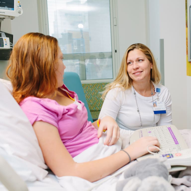 behavioral health provider listening as a teen girl talks to her from her hospital bed