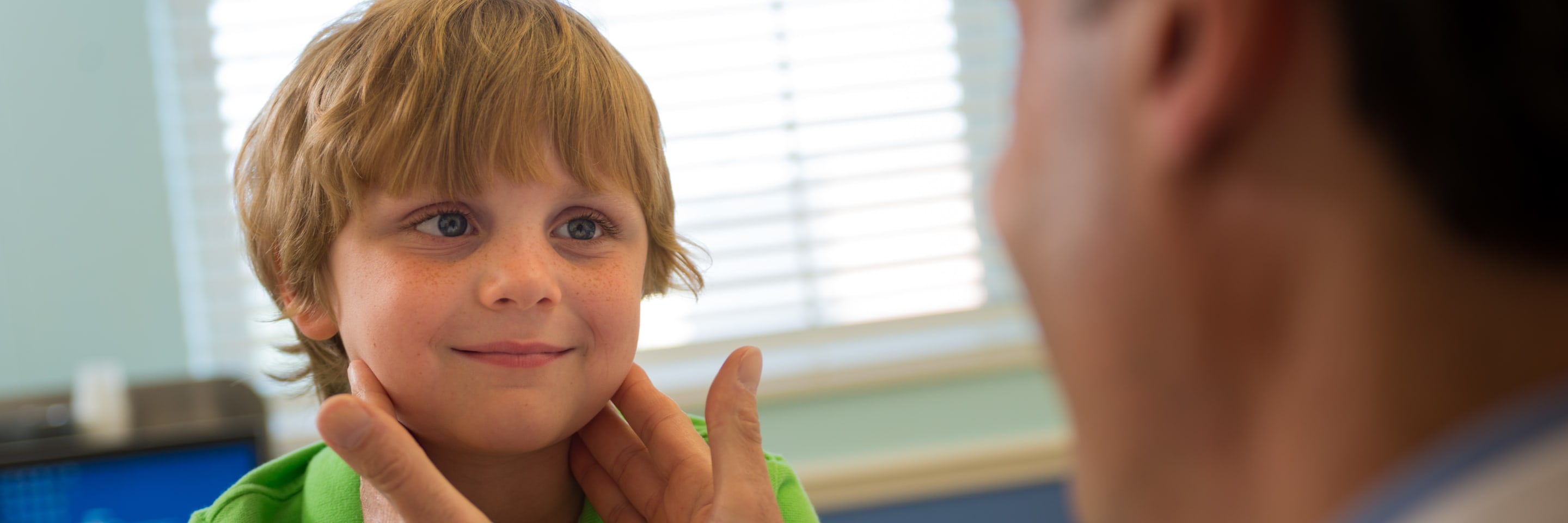 smiling little boy having the lymph nodes in his neck checked by Ear, nose & throat specialist at Wolfson Children's