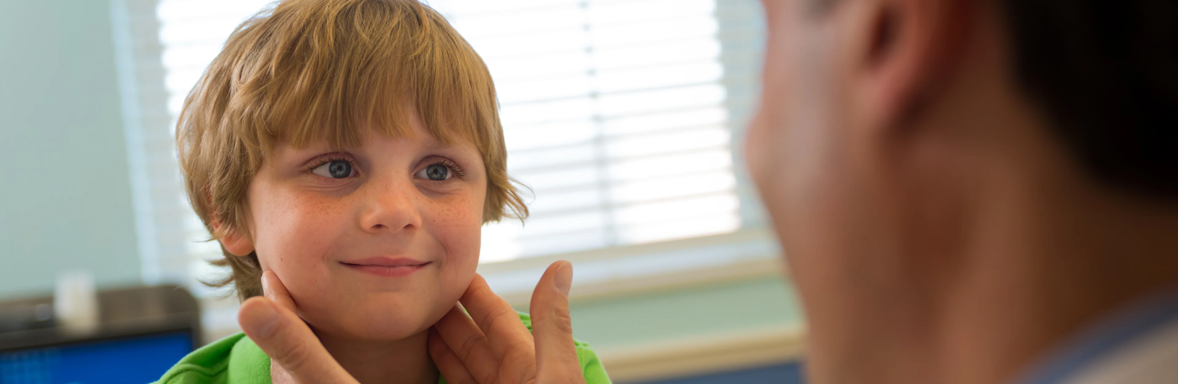 smiling little boy having the lymph nodes in his neck checked by Ear, nose & throat specialist at Wolfson Children's