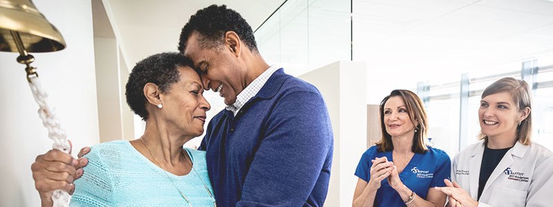 a female patient rings the survivorship bell, her husband by her side, to celebrate the end of treatment.