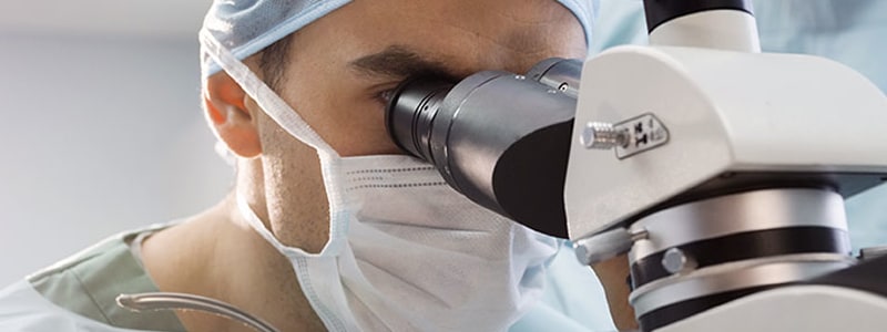 clinical trials - doctor studying sample through microscope