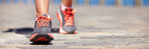 Close up image of person walking down the road in running shoes