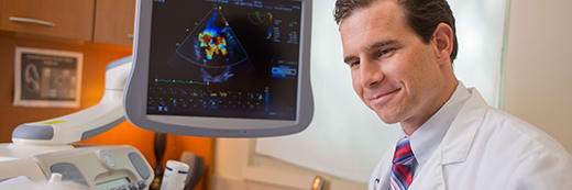 male physician in front of echocardiogram monitor